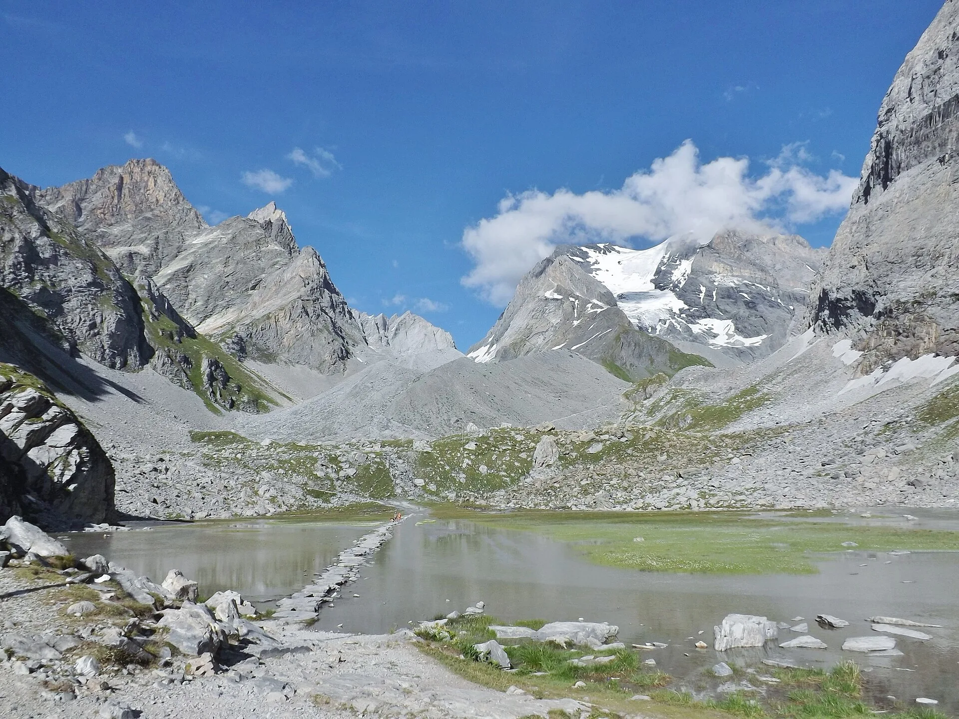Sight of the lac des Vaches lake and its stone footway, at 2,318 meters high in the Vanoise national park in Savoie, France. At the background can be seen the Grande Casse (3,855 m high) and its glacier.